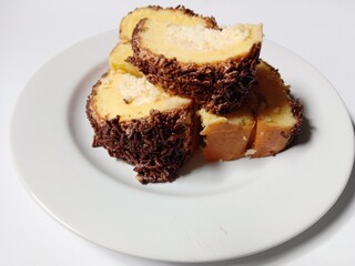 
sponge roll cake with grated cheese filling and sprinkles chocolate topping. 