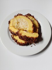 
sponge roll cake with grated cheese filling and sprinkles chocolate topping. 
