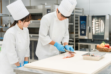 Male and female staff in chef coats preparing fish (chefs, chefs, fresh market, food processing)