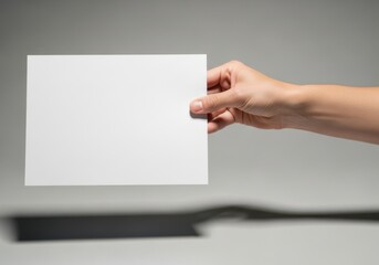 Obraz premium Hand holding blank card for voting or information display against a neutral background