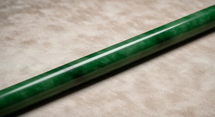 Close-up shot of an elegant, green jade rod on a neutral surface