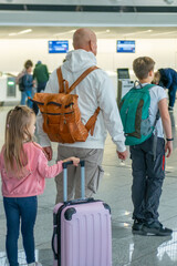 Naklejka premium Large multi-generational family with children, suitcases, and backpacks in airport terminal, ready for long-distance flight, travel concept, checkin counter Airport Frankfurt am Main
