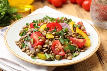 Tasty salad with lentils and vegetables on wooden table, closeup