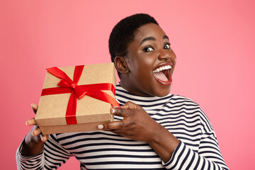 A joyful individual presents a beautifully wrapped gift box with a red ribbon. The scene captures...
