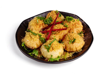 A black plate of Dahi Puri an Indian street food snack from Mumbai, made of crispy, puffed mini-puri shells isolated on white