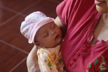 Close-up of a tiny newborn baby's tightly curled fist resting in a comforting embrace.