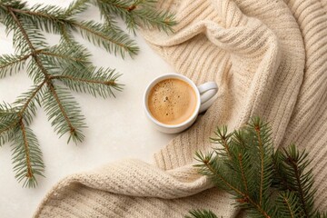 Cappuccino cup on beige knit fabric with pine leaves