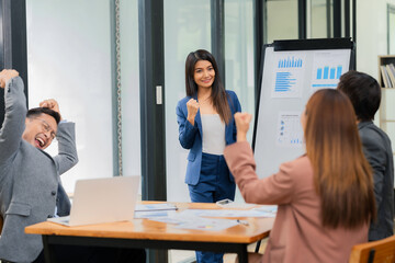 A group of young Asian businessmen and women applaud each other after a successful meeting or presentation in the office.