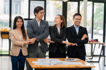 A team of successful Asian businesspeople shake hands and celebrate successful teamwork and goal achievement.
