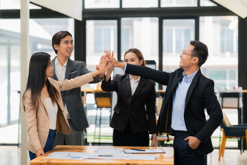 A team of successful Asian businesspeople shake hands and celebrate successful teamwork and goal achievement.