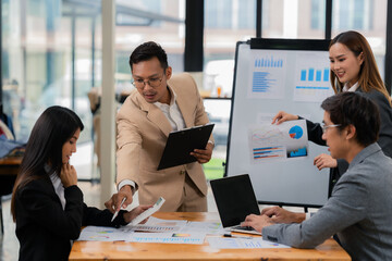Group of business people discussing business plan in office conference room. Project planning, creative brainstorming, discussing ideas, using documents, digital devices.