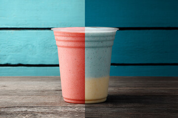 Two-tone blended smoothie, split red and blue/yellow, set against a turquoise wooden background.
