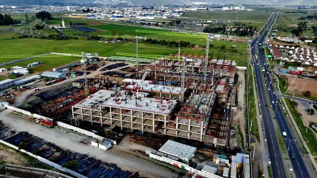 Aerial drone view of a large hospital construction site with cranes and concrete structure in progress.