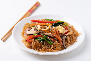 Japchae, Korean stir fried glass noodles with vegetables, pork, soy sauce and sesame seed on white background