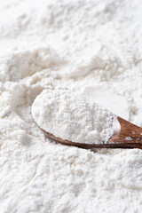 Close-up of white flour in wooden spoon background.