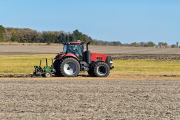 Obraz premium Red tractor cultivating a field for planting