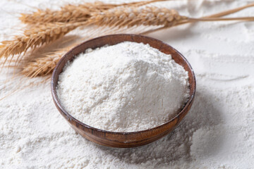 white flour in wooden bowl with wheat ear