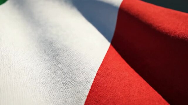 Close-up of a textile surface with three vertical colored stripes green white and red A strong diagonal shadow crosses the white section