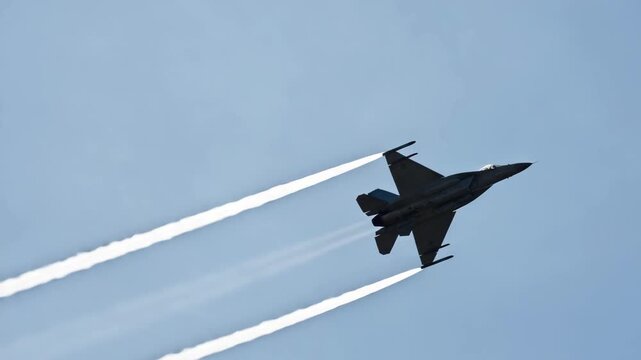 Fighter Jet Performing Aerobatic Maneuvers with Smoke Trails Against a Clear Blue Sky.