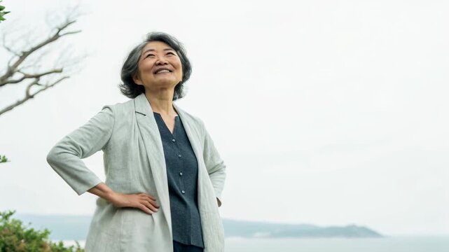 Smiling older woman senior woman elderly woman asian woman gray hair standing outdoors seaside jacket confident elderly woman looking upward serene