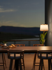 Coffee with bread and book on wooden dining table and chair across balcony in dim cafe or restaurant