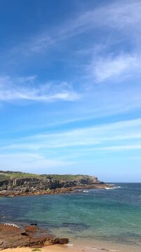 View of little bay, nsw, Australia from cliff top looking down on turquoise water, rocks and swimmer. Buchan point in the distance.