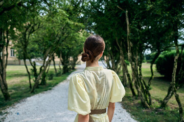 Fototapeta premium Woman dress walking back park pathway summer nature bun elegant authenticity inclusivity