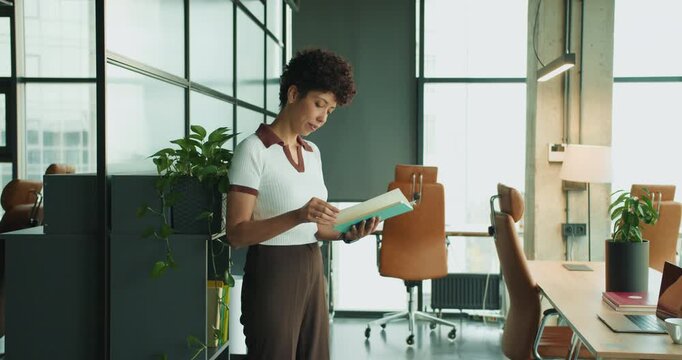 Black woman focusing on project document in contemporary office environment