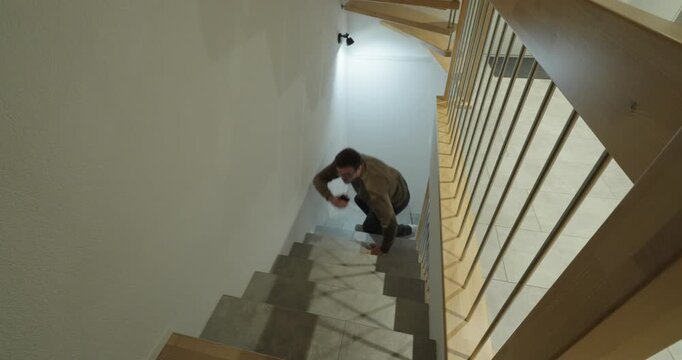 A man walks down a staircase while staring at his smartphone, losing attention and stumbling, highlighting the dangers of distraction, unsafe phone use, and increased fall risk on stairs.