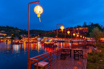 Traditional Chinese-style tourist boats in dam or lake at night, against mountain hills of Baan Rak Thai, Mae Hong Son, Thailand