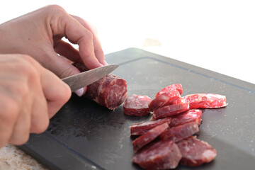 mani che tagliano un salame con un coltello