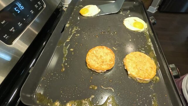 Cooking breakfast with eggs and hash browns on a griddle in a kitchen during the morning