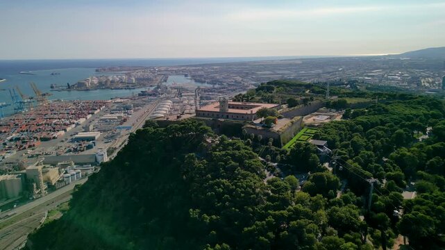 Epic Barcelona Montjuic castle aerial orbit. 
Cinematic 4K drone push-in panorama of 
historic fortress on mountain peak 
and industrial port in Spain.
