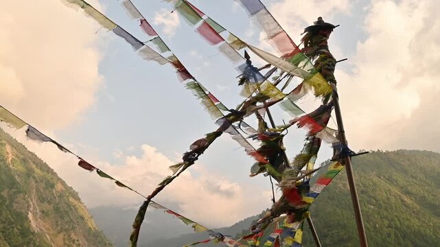 Prayer flags blowing by the wind on mountain in Nepal. The prayer flags initiate peace and good tidings, their sacred mantras etched on the wind.