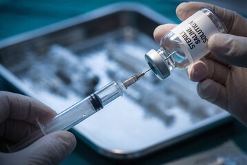 Close-up of a healthcare professional drawing sterile saline solution into a syringe, highlighting safe injection practices in a clinical setting.