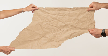 A torn piece of craft paper in the hands of a man and a woman with free space for inscriptions