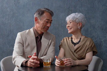 ウィスキーを飲むシニアの夫婦　黒背景