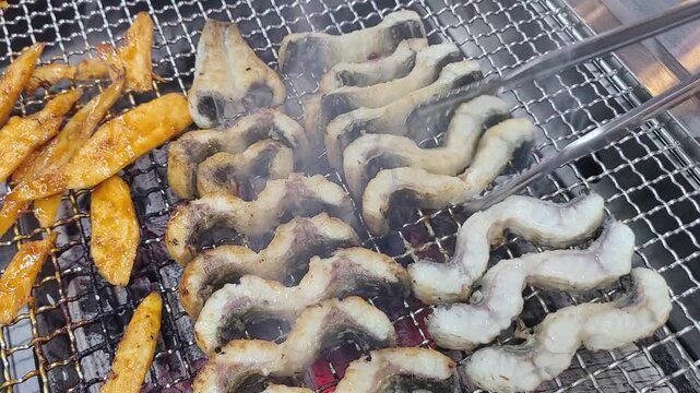 숯불과 철판 위에서 장어구이와 더덕구이를 함께 굽는 한국 음식 조리 장면