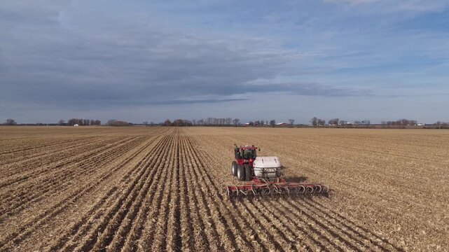 Aerial view of a tractor applying fertilizer in a harvested corn field in preparation for next years planting