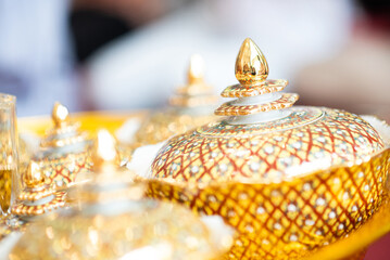 Close-up of traditional Thai Benjarong porcelain ware with intricate gold patterns. Luxury ceramic container with a pointed lid, displaying detailed Thai craftsmanship.