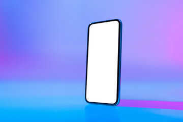 A modern smartphone stands upright against a vibrant gradient background. The screen is blank, providing space for customization or application display. Colors blend smoothly from blue to purple. © Prostock-studio