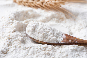 Close-up of white flour in wooden spoon background.