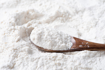 Close-up of white flour in wooden spoon background.