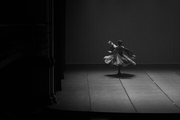 black and white photo, dramatic ballet dancer spinning on stage, spotlight performance, black and white artistic expression, solo performer motion blur