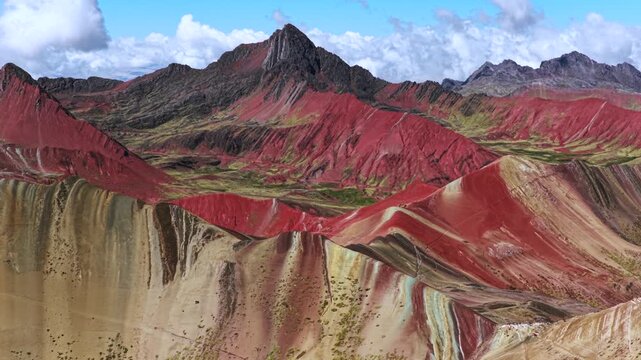 Rainbow Mountain Vinicunca Peru Per&uacute; aerial drone morning blue sky Monta&ntilde;a de Siete Colores Palccoyo clouds Peruvian Andes Red Valley striped hills seven colored Cusco Region backwards pan up motion