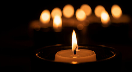 Softly flickering candlelight in darkness, creating a serene and peaceful atmosphere with a gentle glow and bokeh effect
