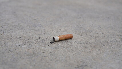 Discarded cigarette butt resting on a concrete surface, a symbol of waste and pollution