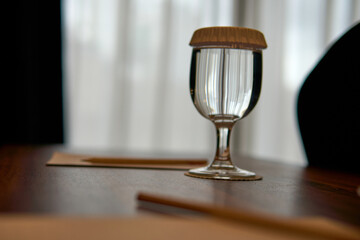Water Glass with Paper Cover and Pencil on Wooden Table