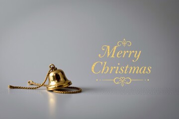 A simple holiday layout featuring a single metal bell with a soft reflection on a plain surface, ample white space, and the phrase "Merry Christmas" elegantly added in sleek lettering.