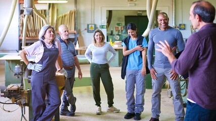 Diverse group of workers listening to a supervisor in workshop